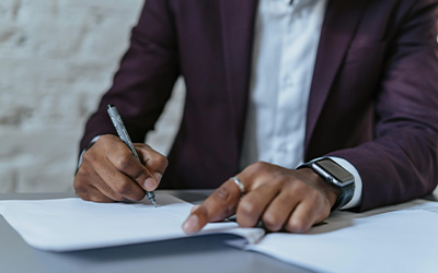 Hands and torso of man signing a contract with his write hand holding a ball point pen